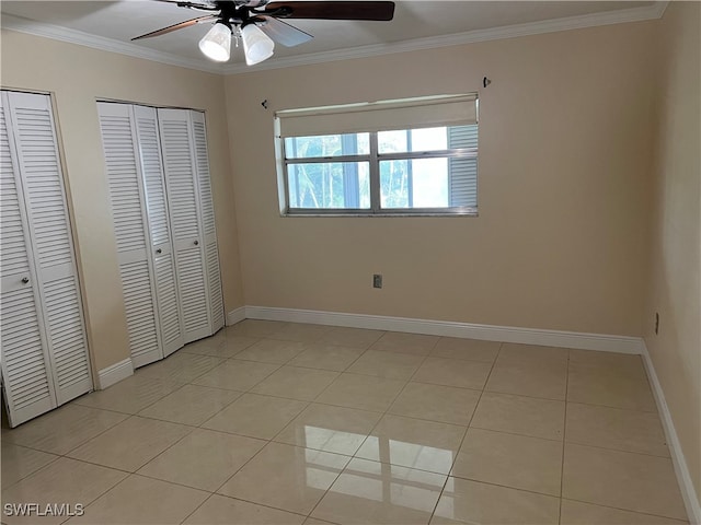 unfurnished bedroom featuring ceiling fan, crown molding, light tile patterned floors, and two closets