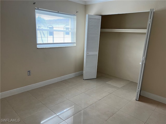 unfurnished bedroom featuring ornamental molding, light tile patterned floors, and a closet