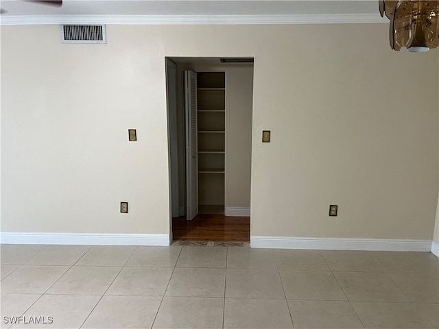 empty room with light tile patterned floors and crown molding