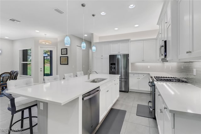 kitchen with pendant lighting, stainless steel appliances, a breakfast bar area, and an island with sink