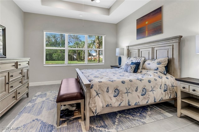 bedroom featuring light tile patterned flooring and a tray ceiling