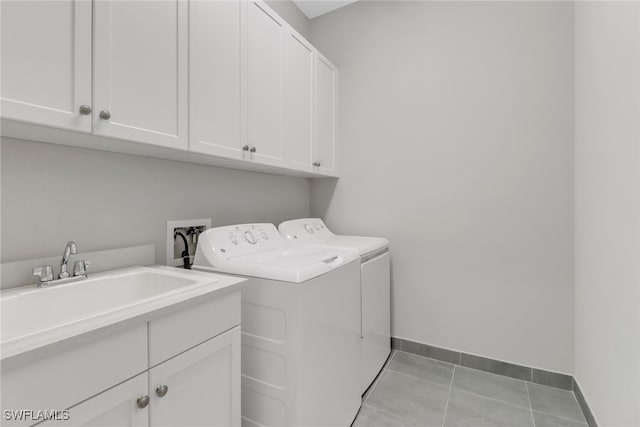 clothes washing area with cabinets, sink, light tile patterned floors, and separate washer and dryer