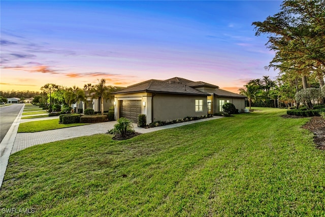 property exterior at dusk featuring a garage and a lawn