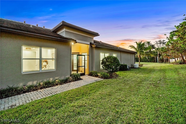 property exterior at dusk featuring a lawn