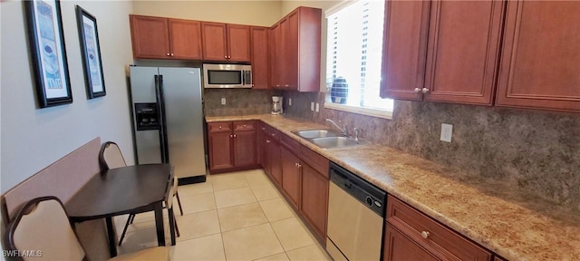 kitchen featuring sink, stainless steel appliances, tasteful backsplash, light stone countertops, and light tile patterned flooring