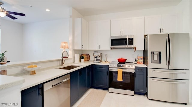 kitchen featuring white cabinetry, sink, ceiling fan, stainless steel appliances, and blue cabinetry