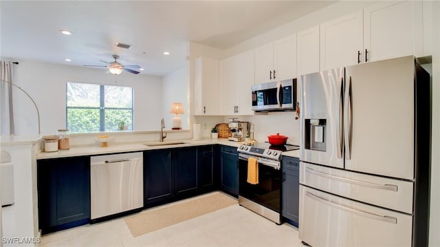 kitchen with sink, white cabinets, ceiling fan, stainless steel appliances, and blue cabinetry