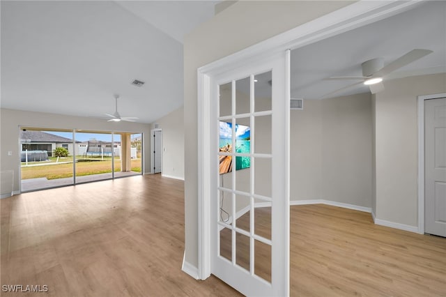 hallway with light wood-type flooring and vaulted ceiling