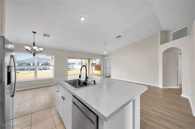 kitchen featuring stainless steel appliances, sink, an island with sink, white cabinets, and light hardwood / wood-style flooring