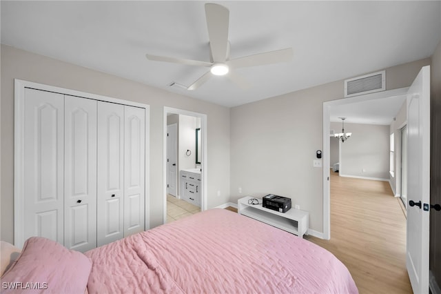 bedroom with light hardwood / wood-style floors, ceiling fan with notable chandelier, connected bathroom, and a closet