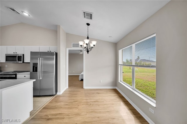 kitchen featuring stainless steel appliances, vaulted ceiling, an inviting chandelier, white cabinetry, and light hardwood / wood-style flooring