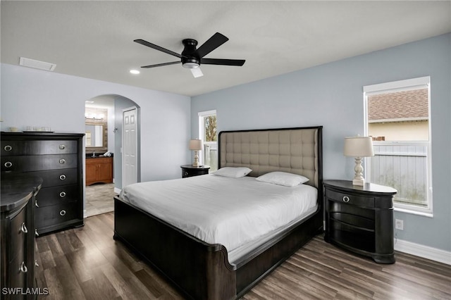 bedroom with ensuite bath, ceiling fan, and dark hardwood / wood-style flooring