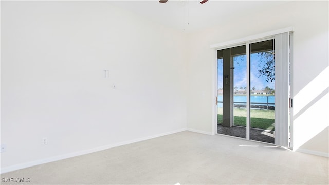 carpeted spare room featuring ceiling fan and a water view