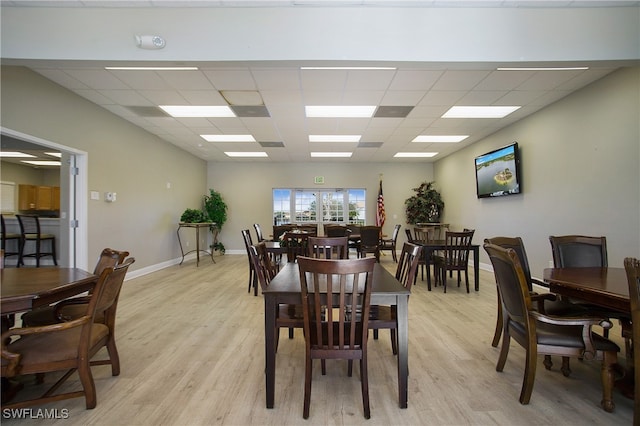 dining space with light hardwood / wood-style floors and a drop ceiling