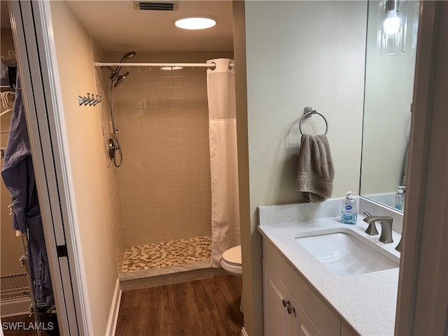 bathroom with hardwood / wood-style floors, walk in shower, vanity, and toilet