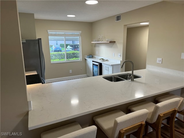 kitchen featuring a kitchen breakfast bar, kitchen peninsula, sink, and stainless steel fridge