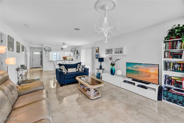 living room with ceiling fan with notable chandelier