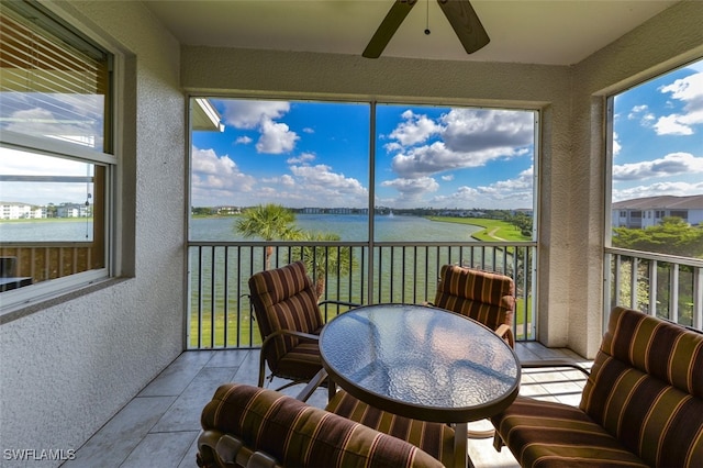 sunroom / solarium with a water view and ceiling fan