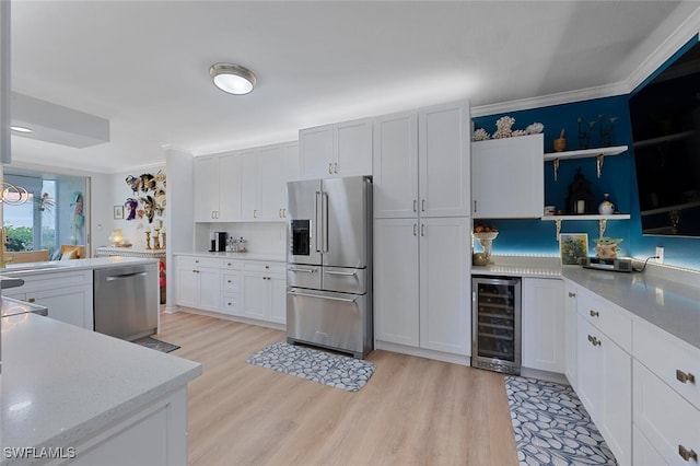 7576 Oleander Gate Dr Unit 101, Naples, FL 34109 - kitchen with stainless steel appliances, wine cooler, light wood-style flooring, white cabinetry, and crown molding