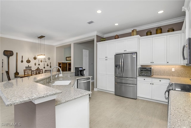 kitchen featuring stainless steel appliances, white cabinetry, sink, hanging light fixtures, and a kitchen island with sink