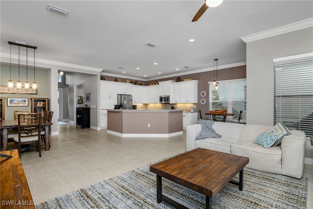 living room featuring ceiling fan with notable chandelier, light tile patterned floors, and ornamental molding