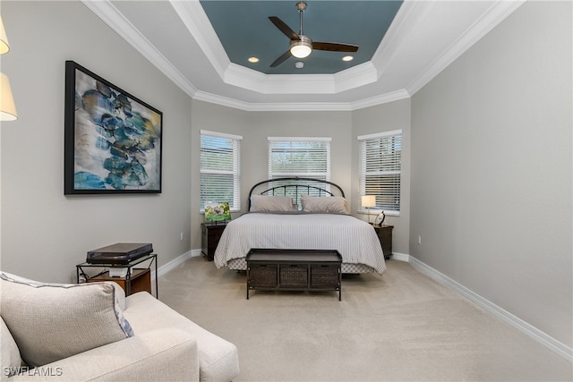 carpeted bedroom with ornamental molding, ceiling fan, and a raised ceiling