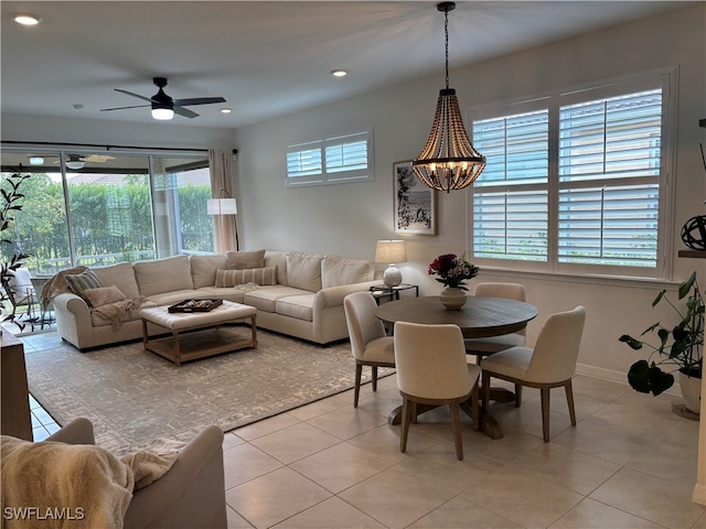 tiled dining room with a wealth of natural light and ceiling fan with notable chandelier