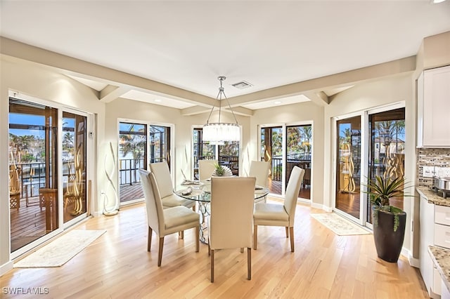 dining room with a chandelier, beam ceiling, and light hardwood / wood-style flooring