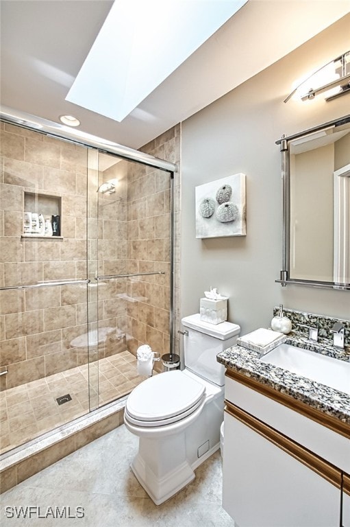 bathroom with toilet, vanity, a skylight, and a shower with door