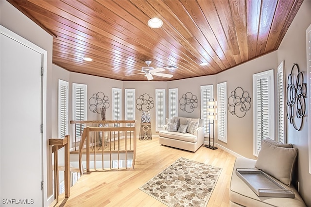 living area featuring hardwood / wood-style floors, ceiling fan, and wooden ceiling