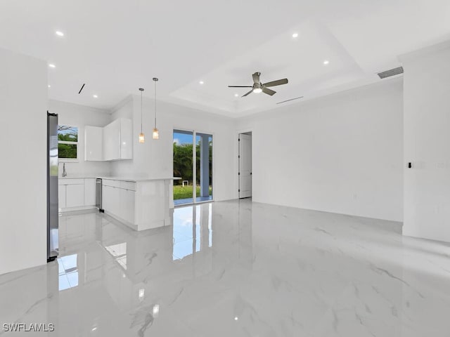 unfurnished living room with a wealth of natural light, ceiling fan, and a raised ceiling