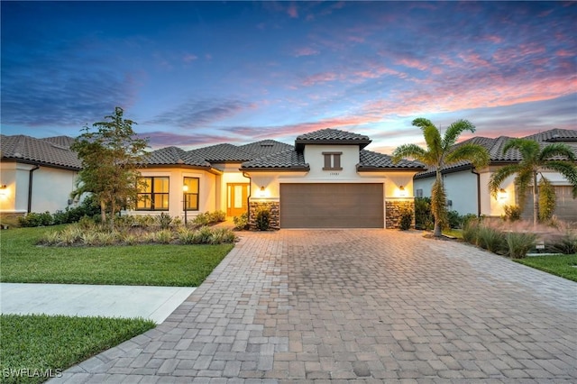 mediterranean / spanish-style home featuring a garage and a lawn