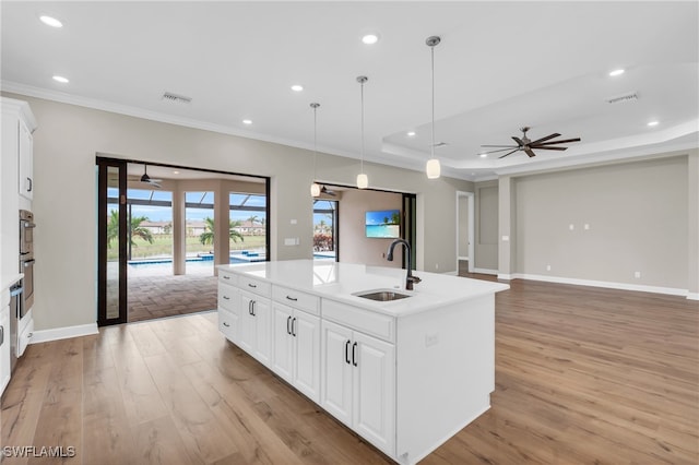 kitchen featuring white cabinetry, ceiling fan, sink, and an island with sink