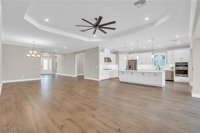 unfurnished living room featuring plenty of natural light, light hardwood / wood-style floors, ceiling fan with notable chandelier, and sink