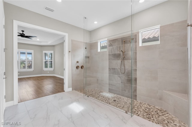 bathroom with hardwood / wood-style floors, a tile shower, a wealth of natural light, and ceiling fan