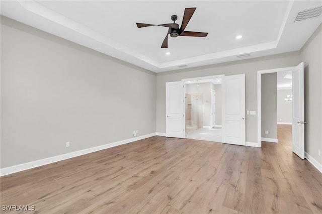 unfurnished bedroom with a tray ceiling, ceiling fan, and light hardwood / wood-style floors