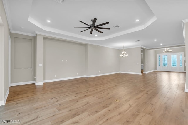 unfurnished living room featuring a tray ceiling, crown molding, light hardwood / wood-style floors, and ceiling fan with notable chandelier