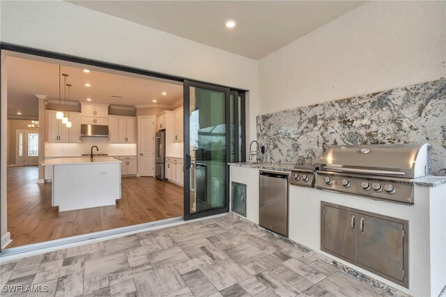 kitchen with pendant lighting, high end refrigerator, kitchen peninsula, stainless steel fridge, and white cabinetry