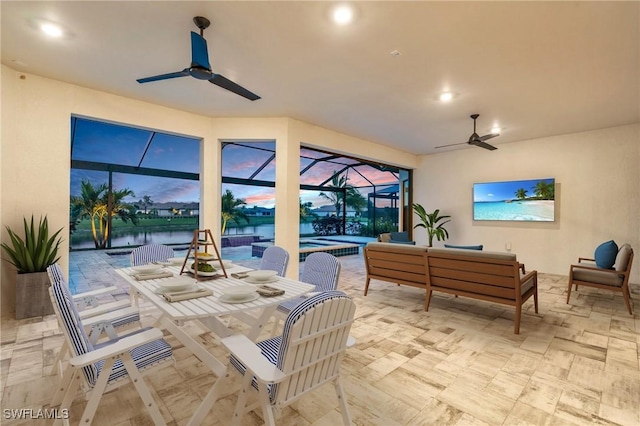 view of patio / terrace with a swimming pool, a lanai, an outdoor hangout area, ceiling fan, and a water view