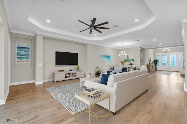 living room with a raised ceiling, ornamental molding, light hardwood / wood-style floors, and french doors