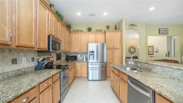 kitchen with light stone countertops, appliances with stainless steel finishes, sink, backsplash, and light tile patterned flooring