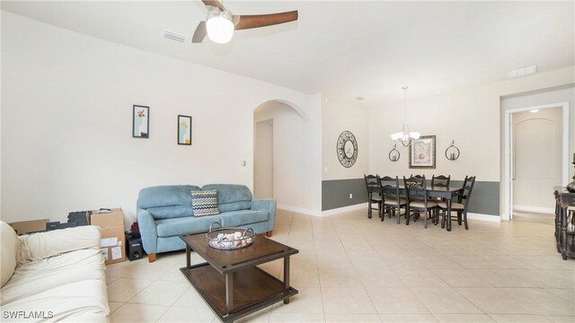 tiled living room featuring ceiling fan with notable chandelier