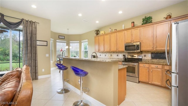 kitchen featuring pendant lighting, stainless steel appliances, tasteful backsplash, light stone counters, and light tile patterned floors