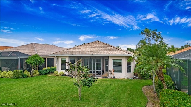 rear view of house with a lanai and a lawn