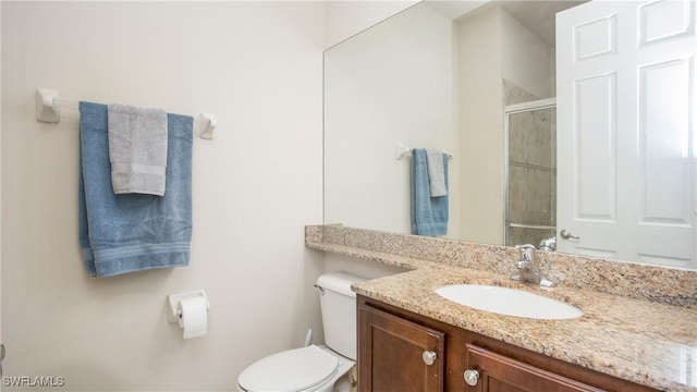 bathroom featuring vanity, toilet, and a shower with door