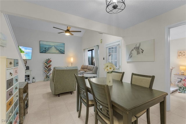 dining area with a textured ceiling, lofted ceiling with beams, ceiling fan, and light tile patterned flooring