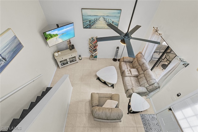 living room with tile patterned flooring, ceiling fan, and a towering ceiling