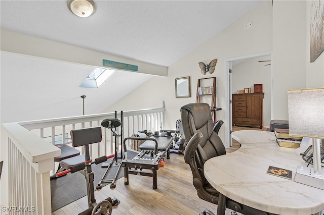 office space featuring light hardwood / wood-style floors and vaulted ceiling with skylight