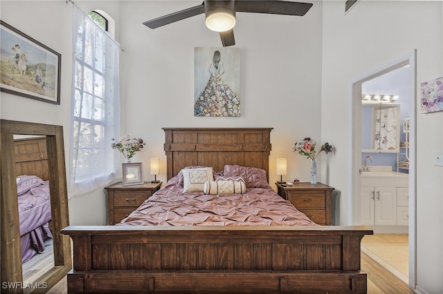 bedroom with ceiling fan, sink, light hardwood / wood-style floors, and ensuite bathroom