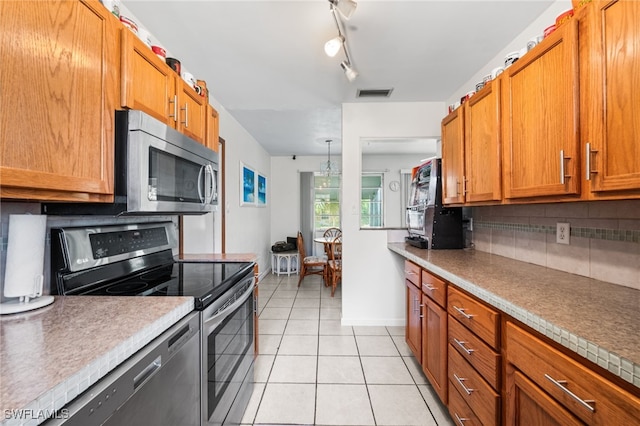 kitchen with decorative backsplash, light tile patterned floors, rail lighting, and appliances with stainless steel finishes